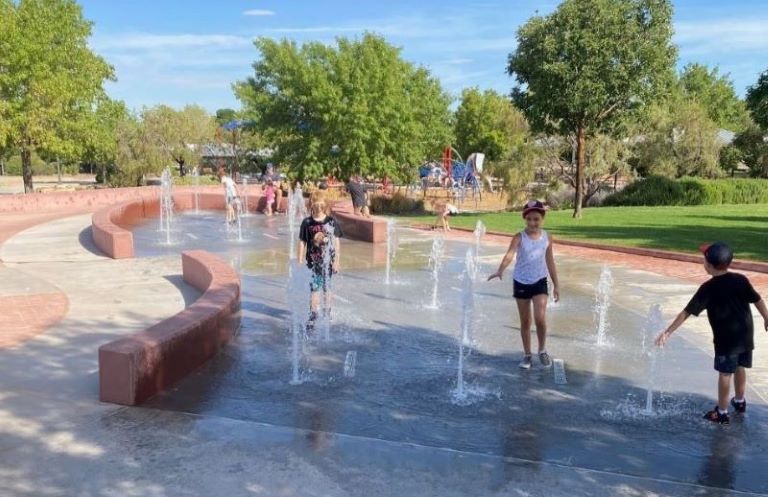 Children playing on a spray pad at a park.